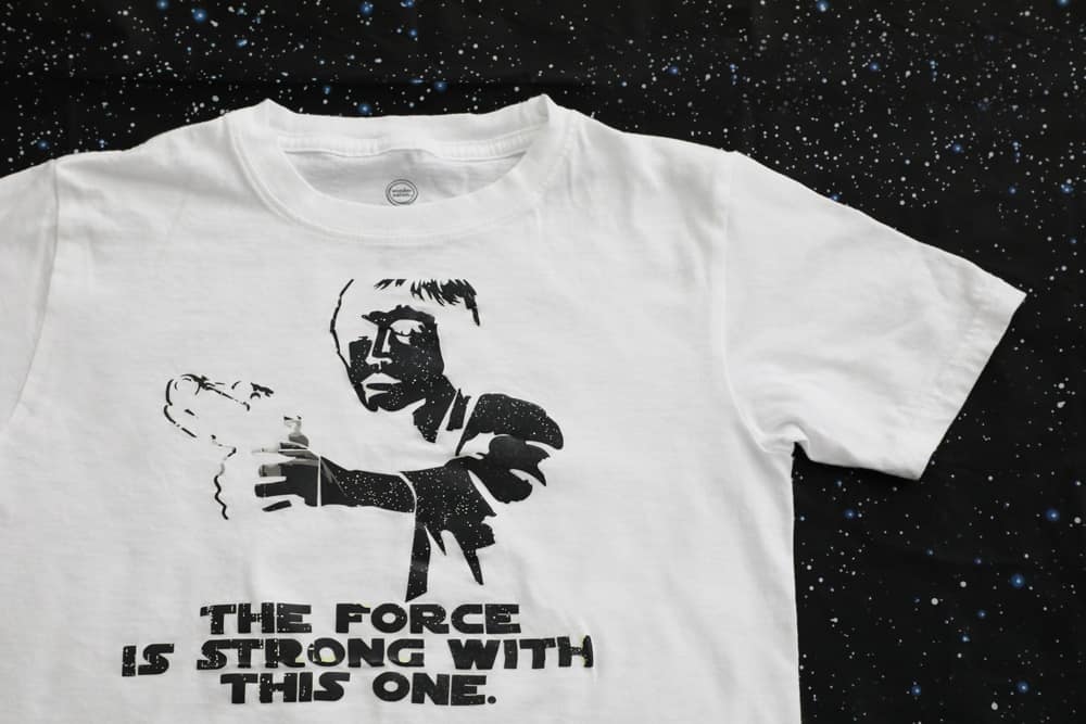 white shirt with a black Luke Skywalker silhouette that says "the force is strong with this one" 