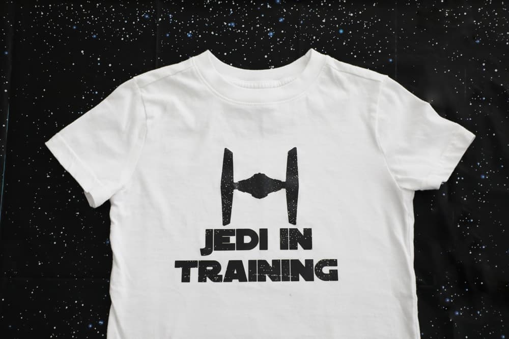 white tee with a fighter pilot and the words "jedi in training" in black