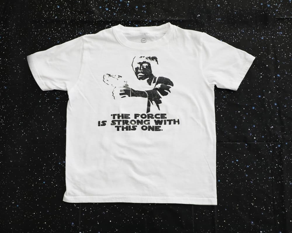 white shirt with a black Luke Skywalker silhouette that says "the force is strong with this one" 