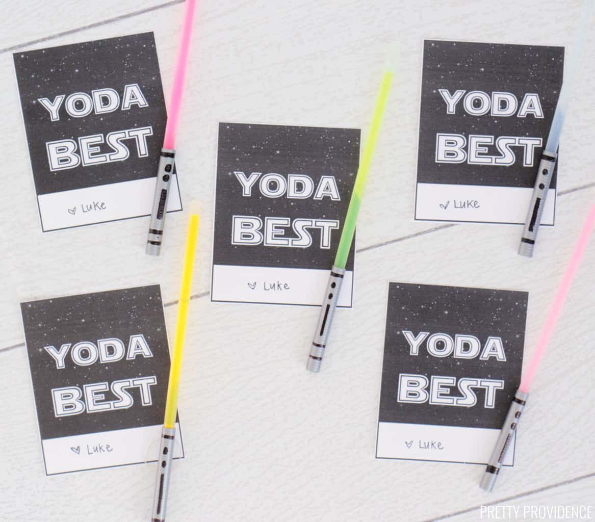Five black and white 'Yoda Best' Star Wars Valentines cards with glow stick light sabers attached to each one on a white surface.