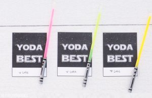 Three 'Yoda Best' Star Wars valentines with glow stick light sabers on a white table.