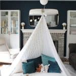 Teepee style blanket fort made with bedsheets and clothesline hung from a light fixture.