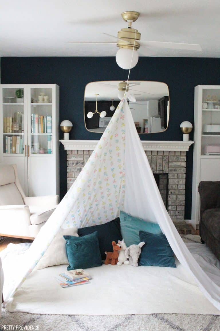 Teepee style blanket fort made with bedsheets and clothesline hung from a light fixture.