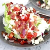 close up of wedge salad with lots of toppings on a small grey plate