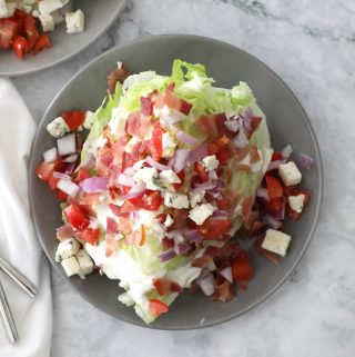 wedge salad on a grey plate on a marble counter with a white napkin on the left