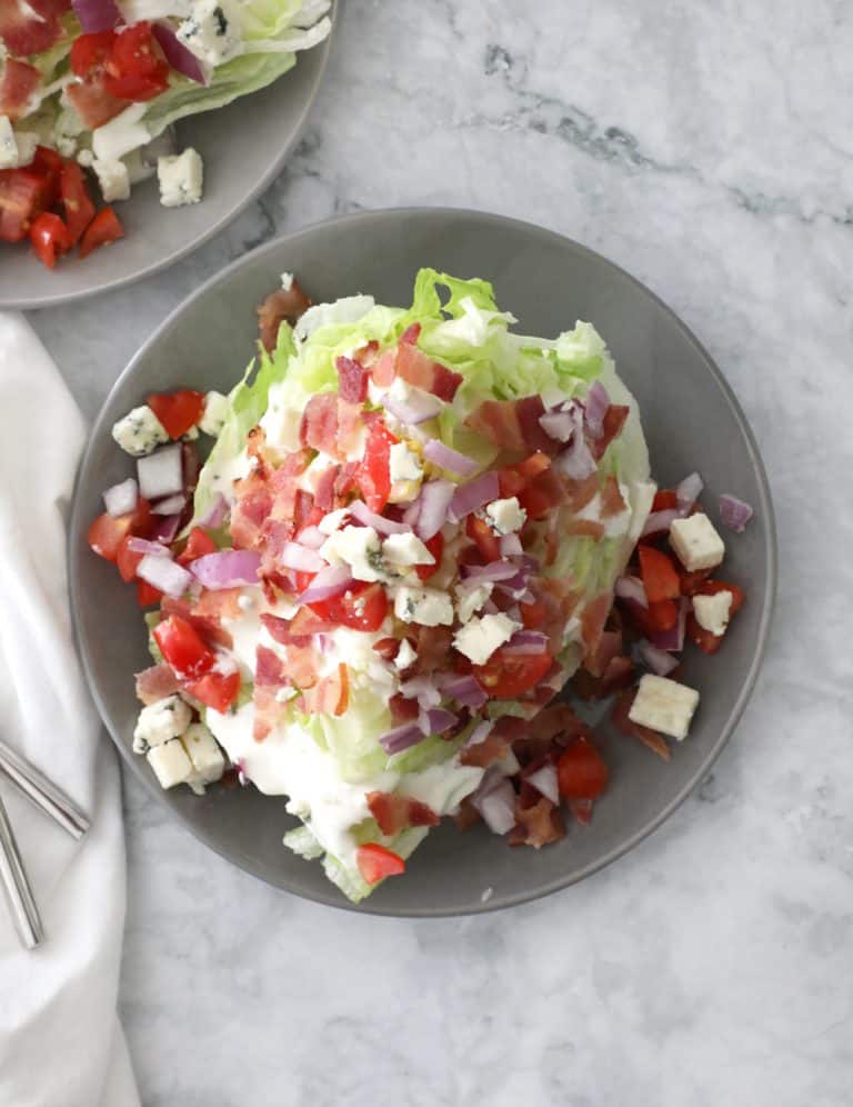 wedge salad on a grey plate on a marble counter with a white napkin on the left