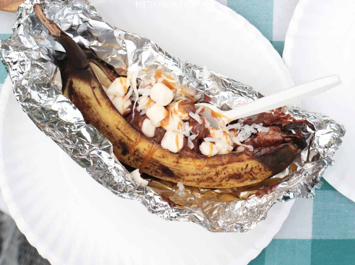 Banana boat in tin foil with marshmallows, chocolate, coconut and caramel sauce.