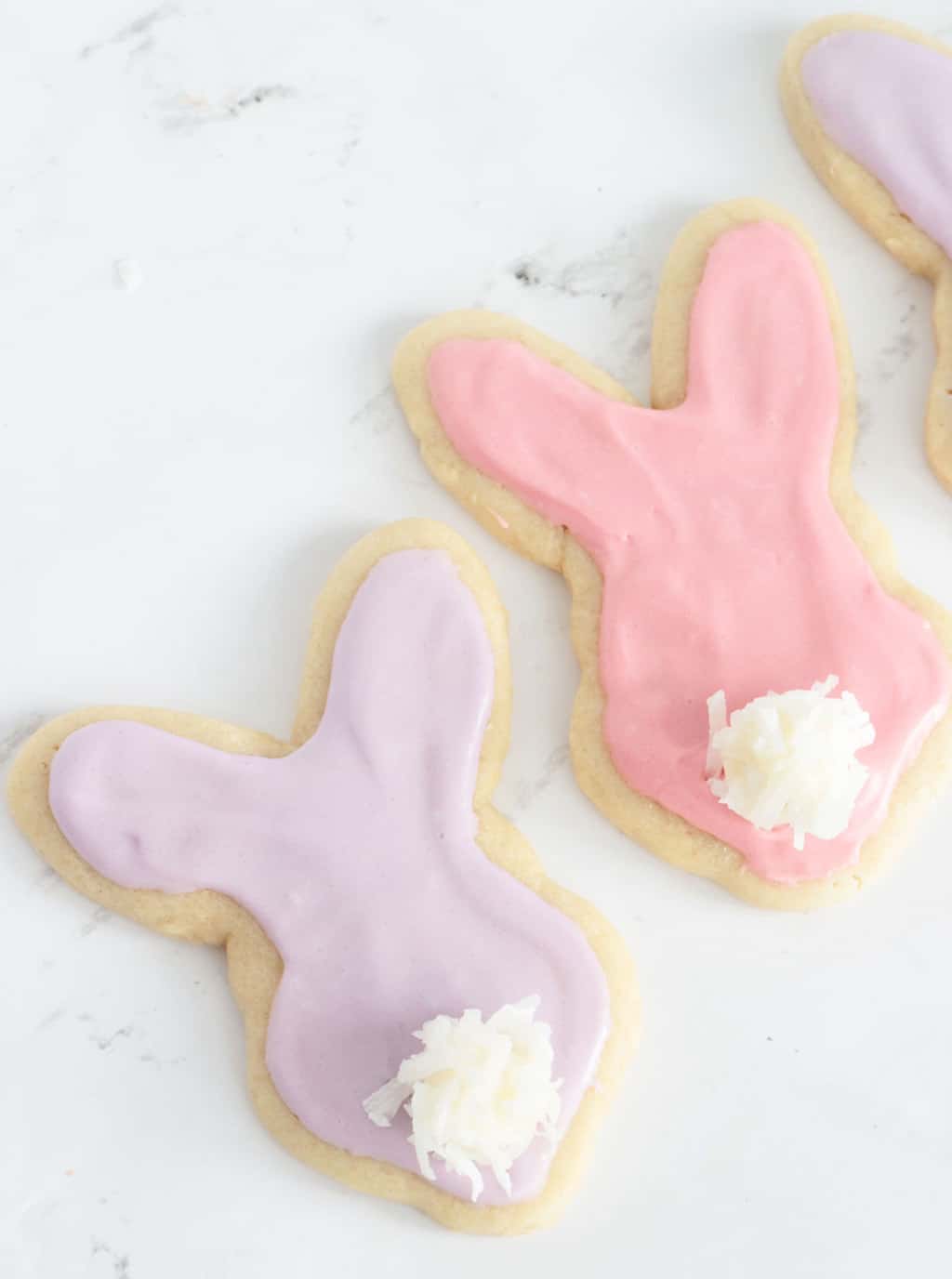 Purple and pink Easter cookies shaped like bunnies with marshmallow coconut tails.