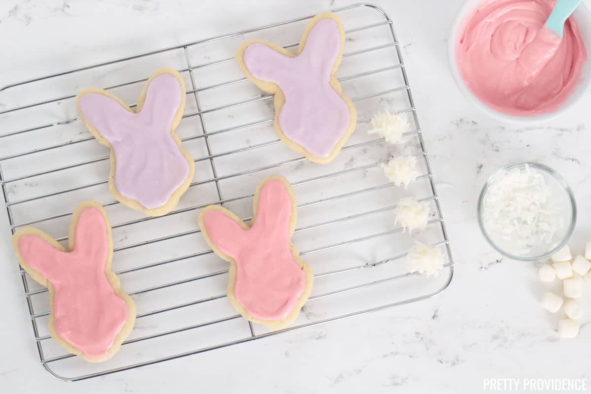 Bunny Easter cookies with pink and purple frosting being decorated.