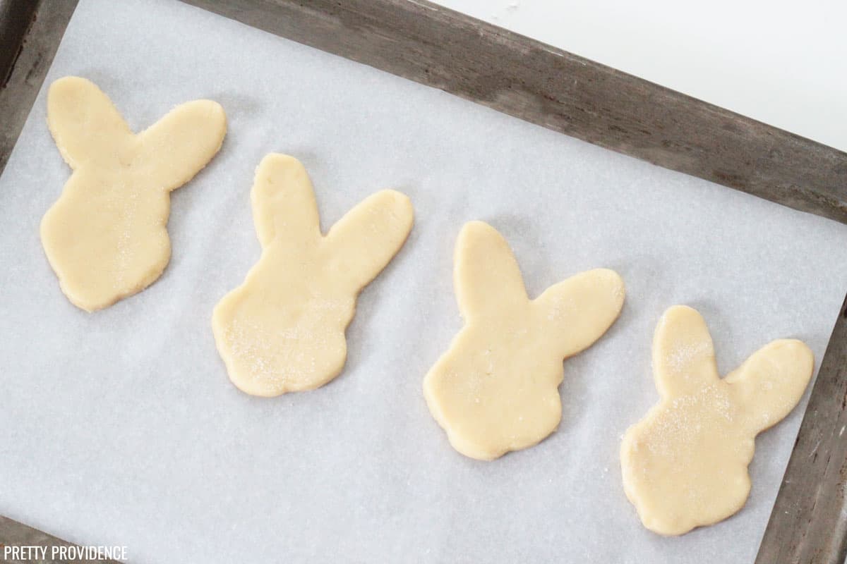 Sugar cookie dough cut with bunny cookie cutter on parchment paper
