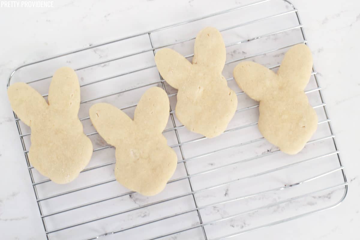 Four Easter bunny shaped sugar cookies on a cooling rack