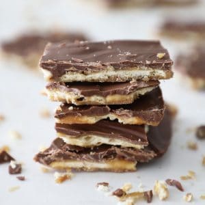stack of saltine toffee on a white counter with crumbs surrounding it