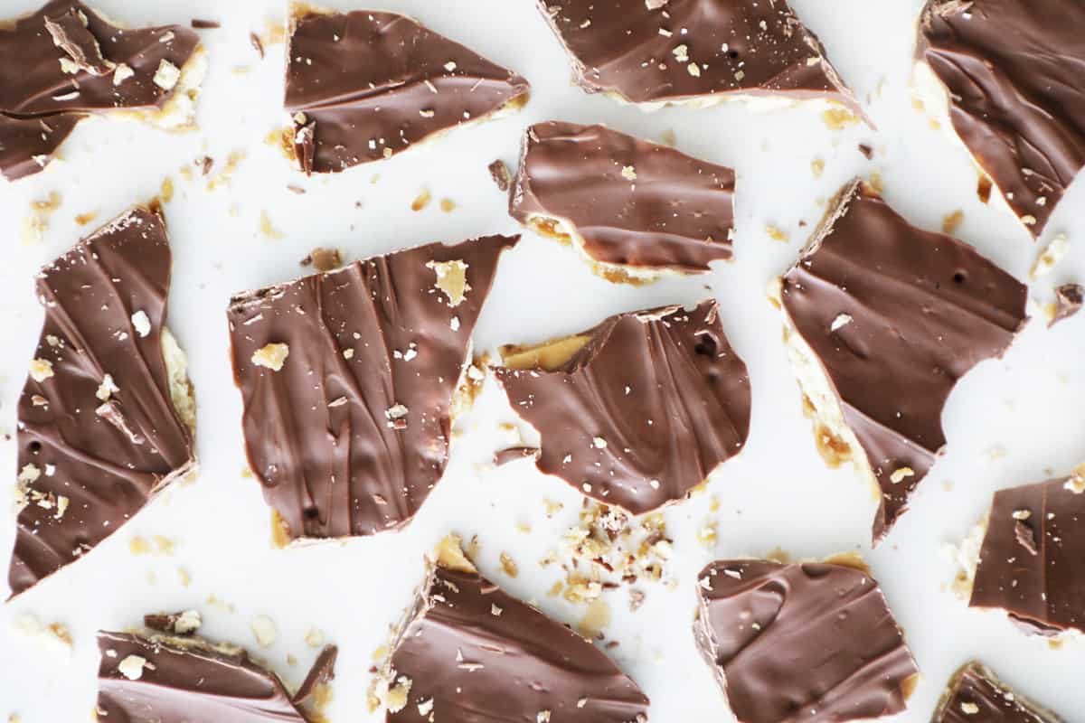 A bunch of cracked up saltine toffee bark and crumbs on a white counter top.