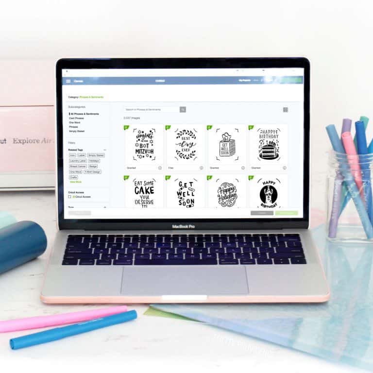 Cricut access on the screen of a Macbook Pro and Cricut supplies around it.