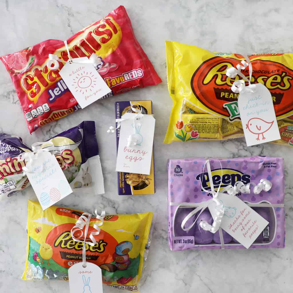 six bags of easter candy with easter gift tags tied on with white ribbon