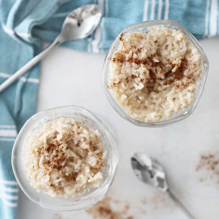 rice pudding on a white counter by some cinnamon and a blue tea towel