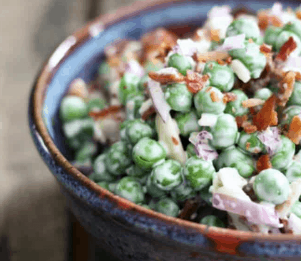 peas and bacon on a dark bowl on a wooden background