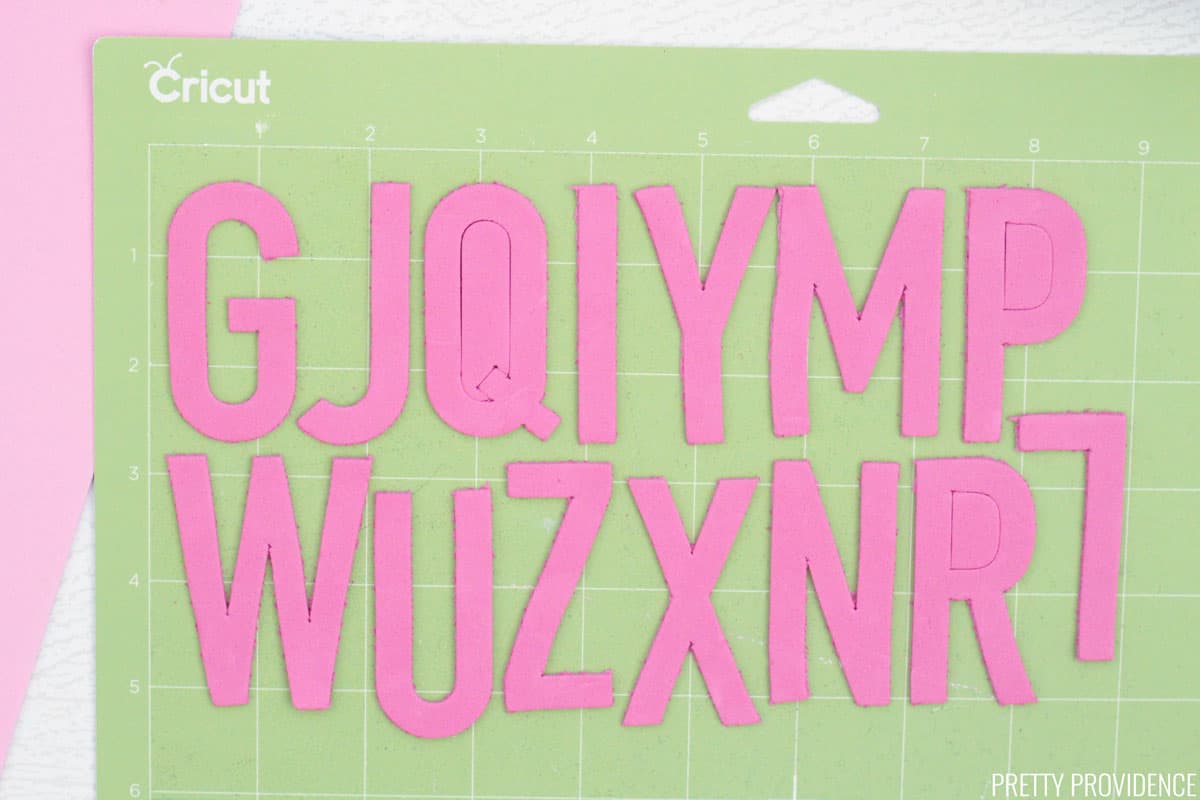 Alphabet letters cut out of craft foam on a green cricut cutting mat