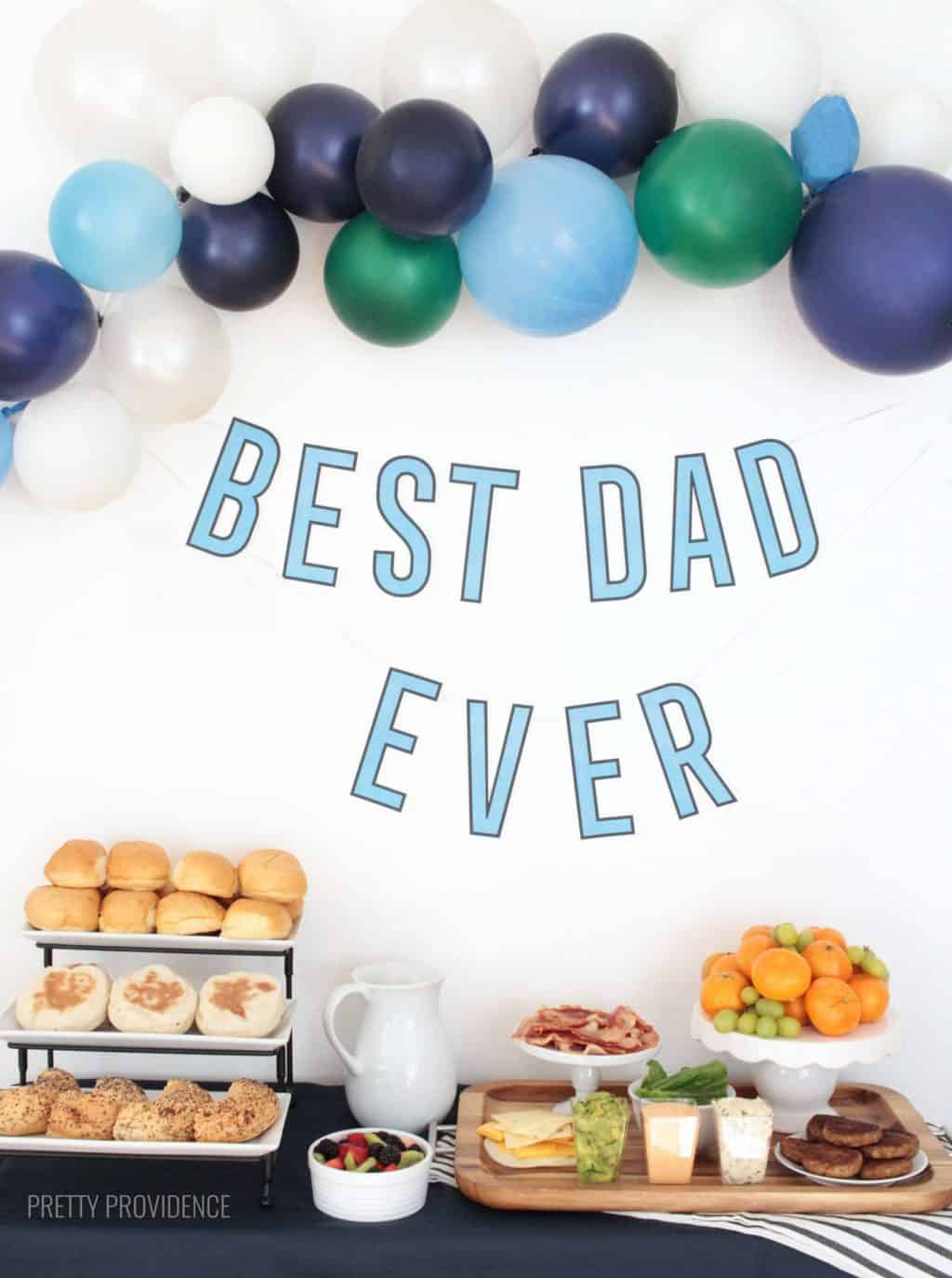 Father's Day breakfast table with breakfast sandwich ingredients, balloons and free printable 'best dad ever' banner.