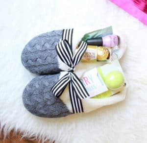 grey slippers filled with treats on a white faux fur rug