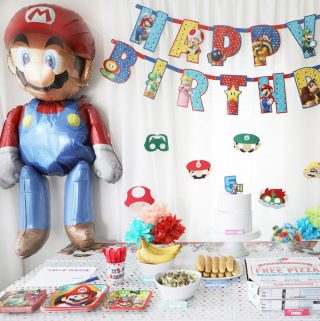 large mario balloon next to a happy birthday banner and party table