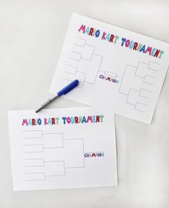 two printable mario kart tournament brackets on a white countertop with a blue sharpie