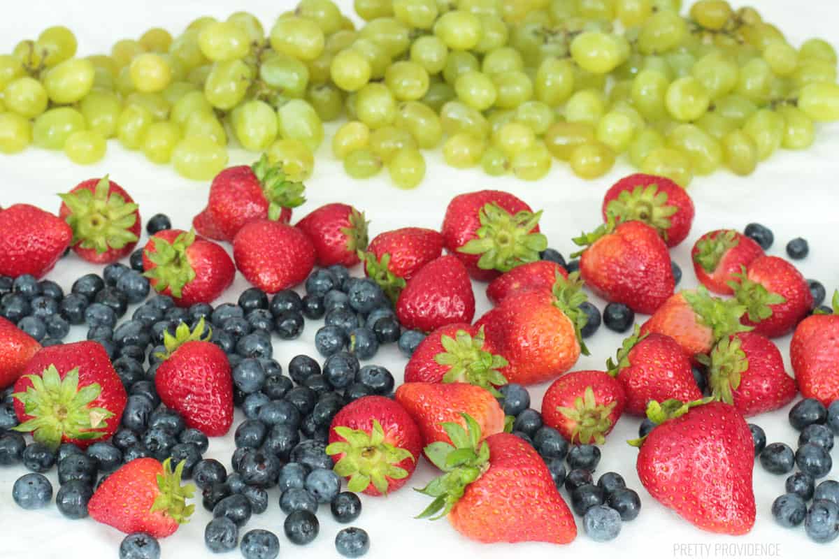 Strawberries, blueberries and grapes drying on paper towels after washing.