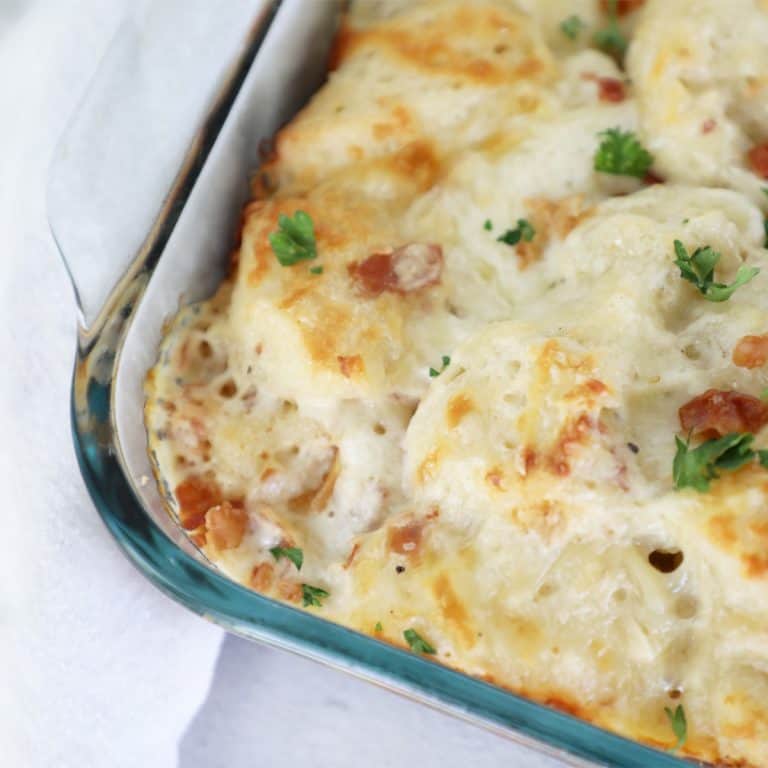 Corner of a pan of carbonara bake, next to a white tea towel