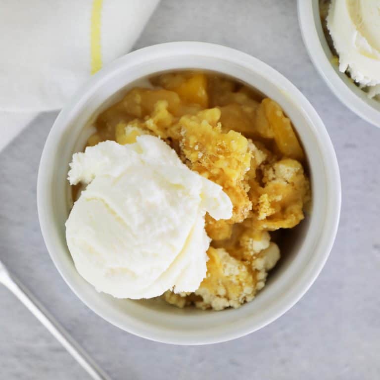 peach cobbler with ice cream in a small white dish