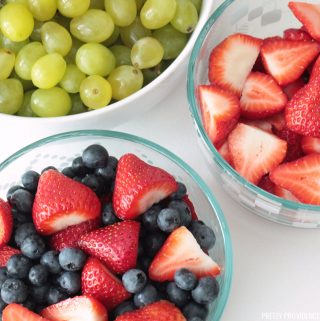 Strawberries, blueberries and grapes washed and prepped in glass bowls.