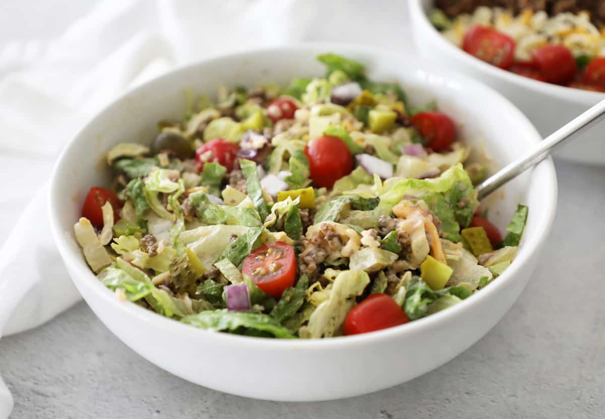 side view of burger salad in a white bowl with a fork sticking out