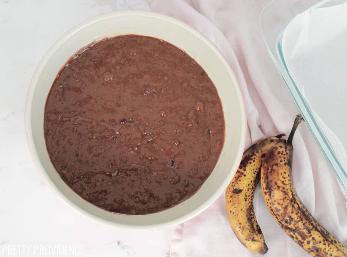 Chocolate banana bread batter in a bowl with bananas to the right