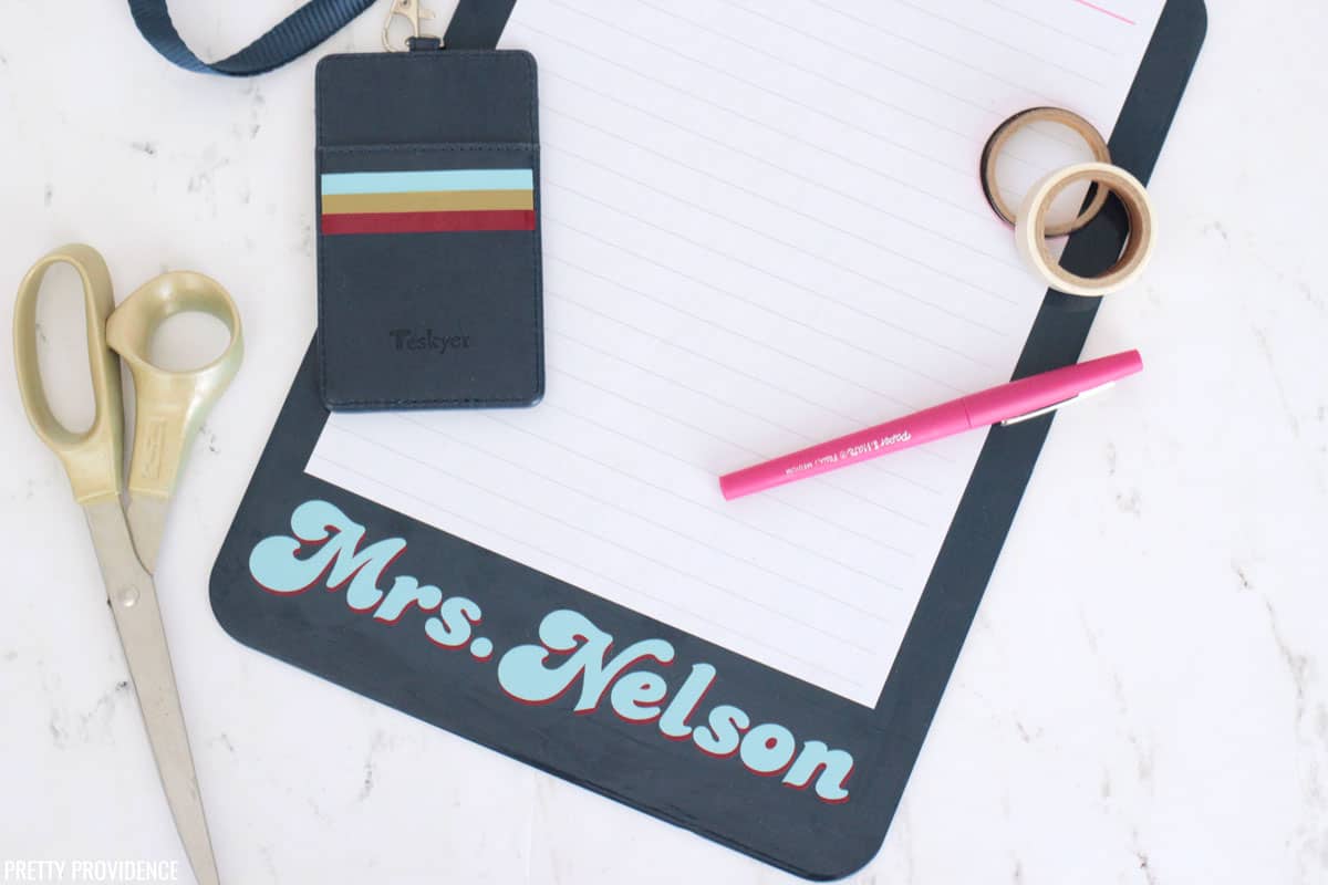 Navy blue clipboard with 'Mrs. Nelson' in vinyl and striped badge holder