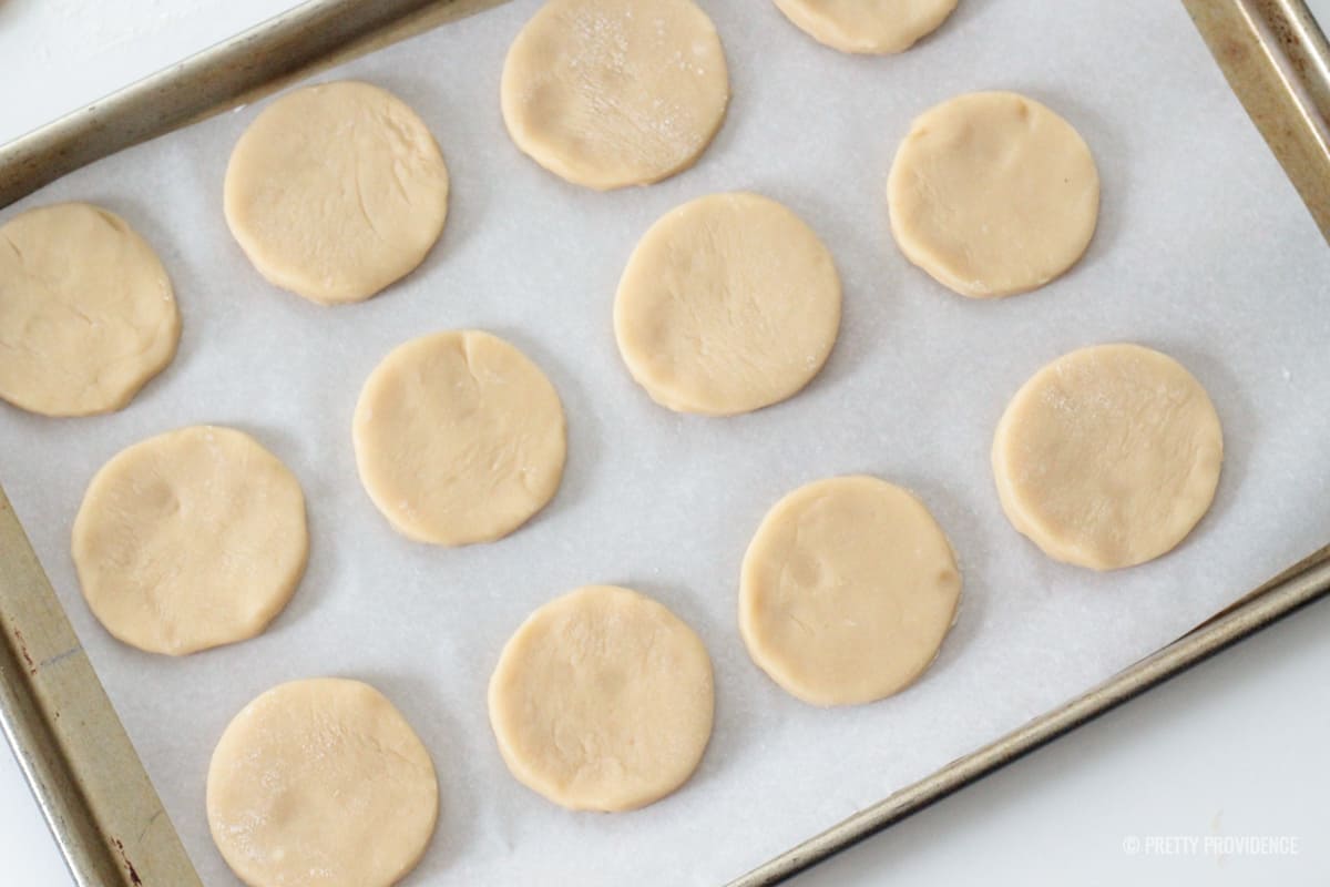 Cut out sugar cookie dough on cookie sheet with parchment paper under