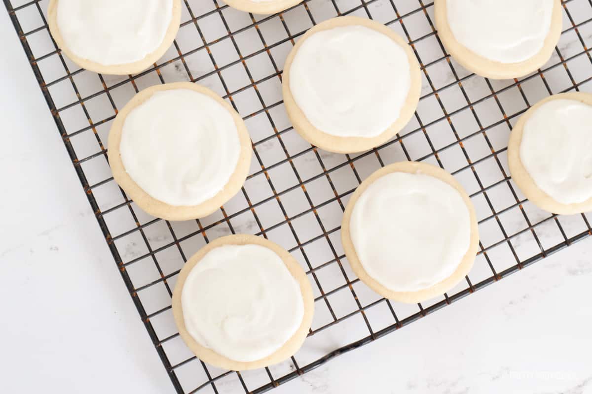 White frosting on top of round cookies on a cooling rack