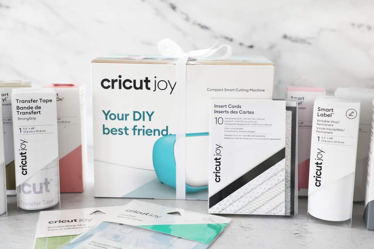 A Cricut Joy in a box with a white bow and accessories around it