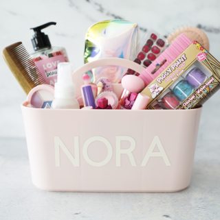 a pink makeup caddy with a name personalized on it filled with supplies