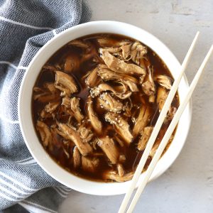 slow cooker teriyaki chicken in a white bowl with chopsticks