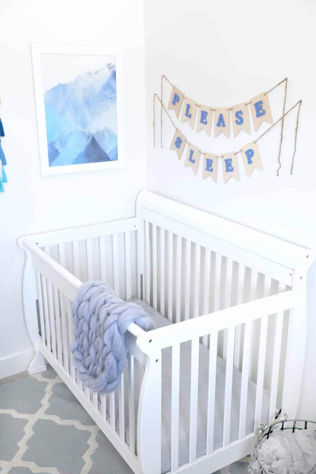 white crib by blue mountain painting with crochet blanket