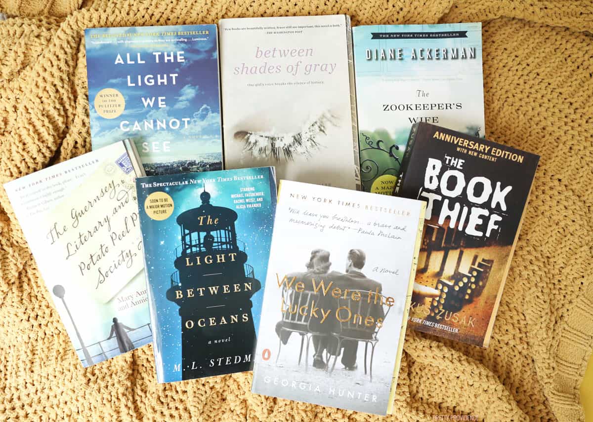 Seven paperback books, all historical fiction about WWII, on a yellow knit blanket