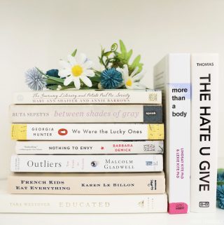 Books with white covers stacked and arranged on a white shelf