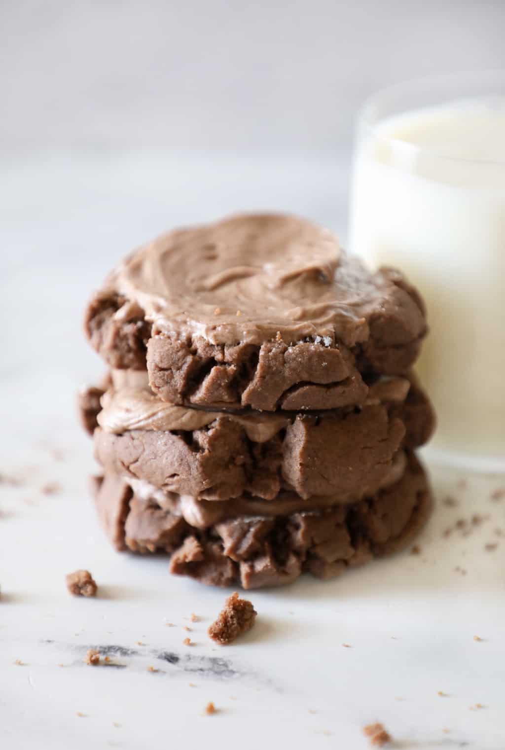 three chocolate cookies stacked near a glass of milk