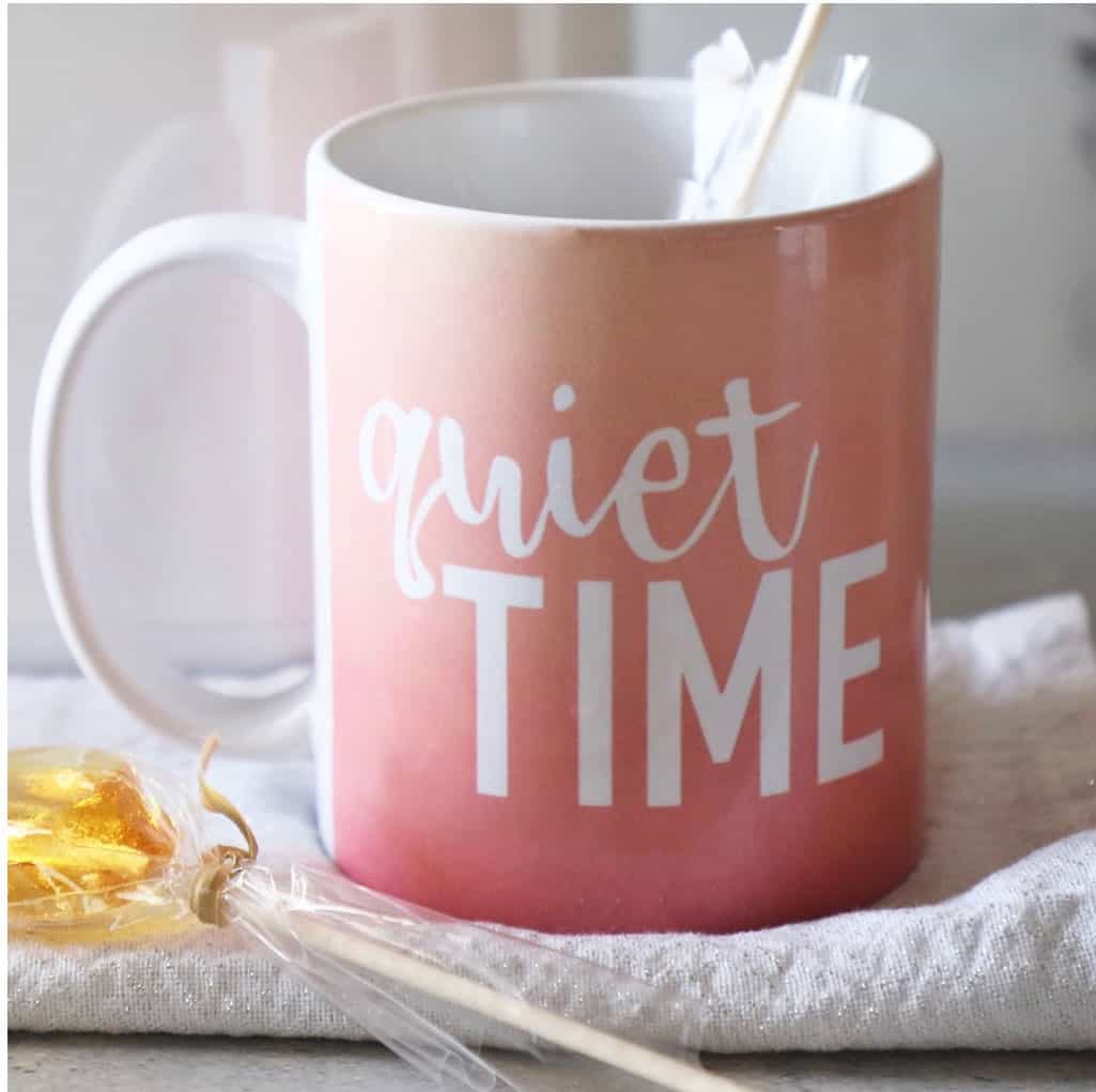 Pink sunset mug that says 'quiet time' on a white tea towel with stirring spoon