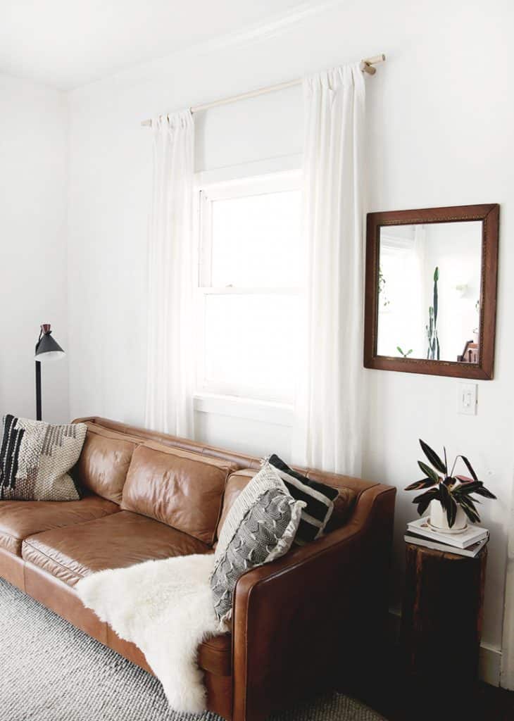 DIY Dowel Curtain Rod with white curtains above a leather sofa