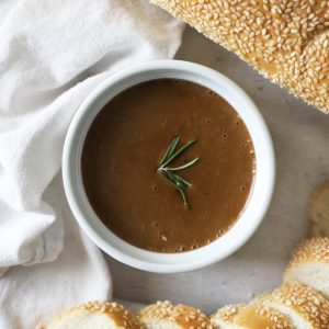 bread dip in a white bowl surrounded by bread and a white linen napkin