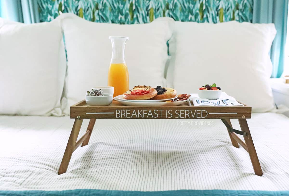 Breakfast in Bed tray with vinyl decal that says 'breakfast is served' on a bed 