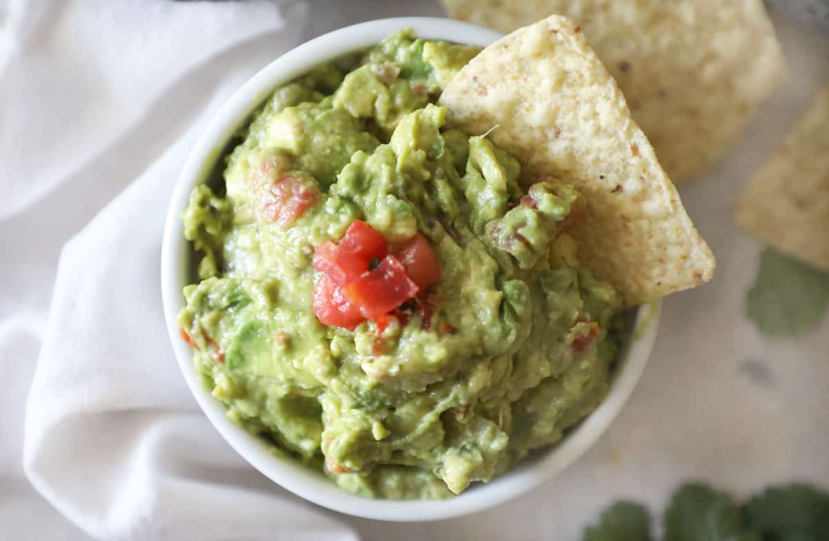 homemade guacamole in a white bowl on a cement countertop