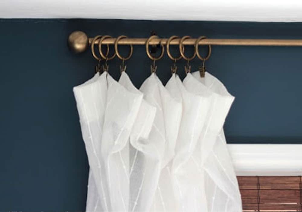 DIY curtain rod brass finish with white curtains against a teal wall