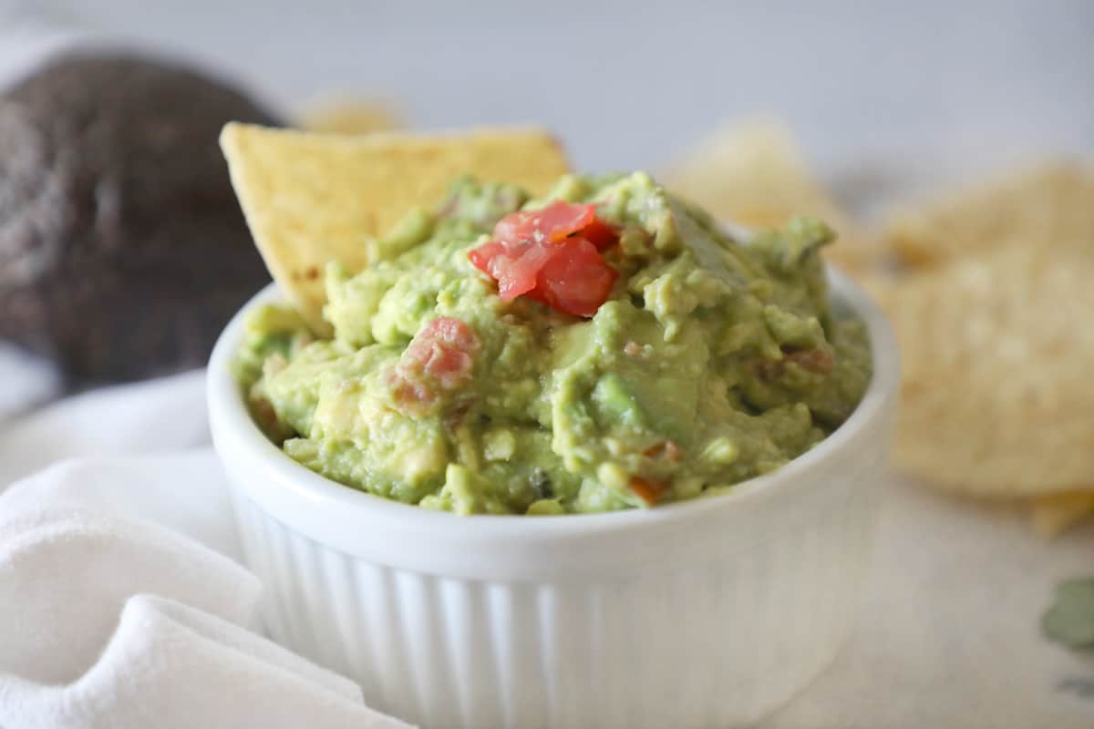guacamole with tomatoes on top and a chip sticking out