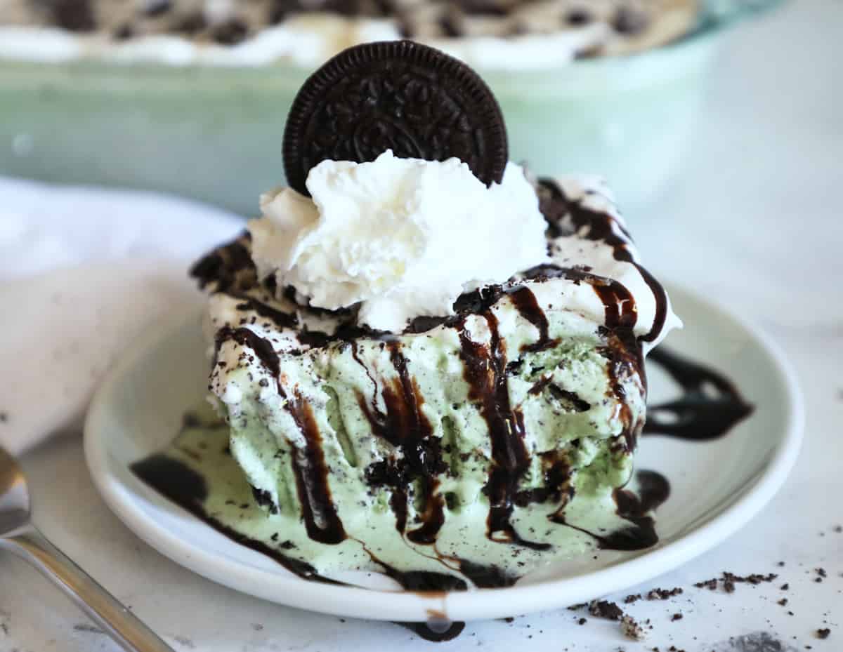 mint chocolate chip ice cream cake on a white plate with whipped cream and an Oreo on top